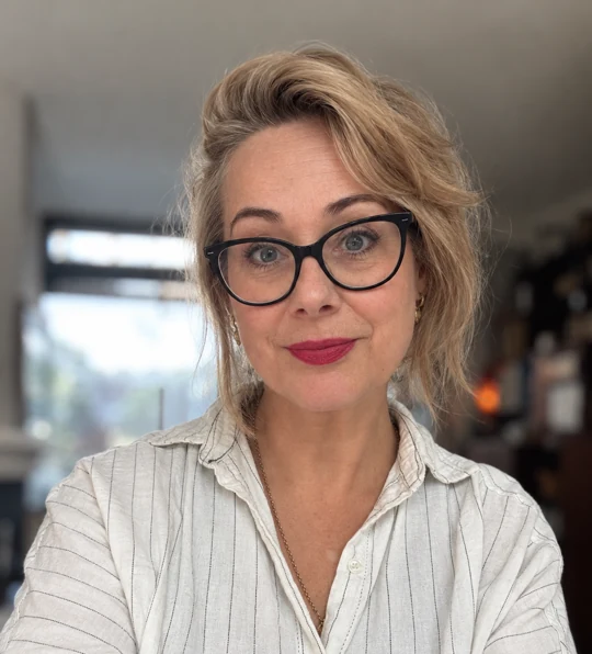 Astrid Bussink wearing glasses and a light striped shirt.
