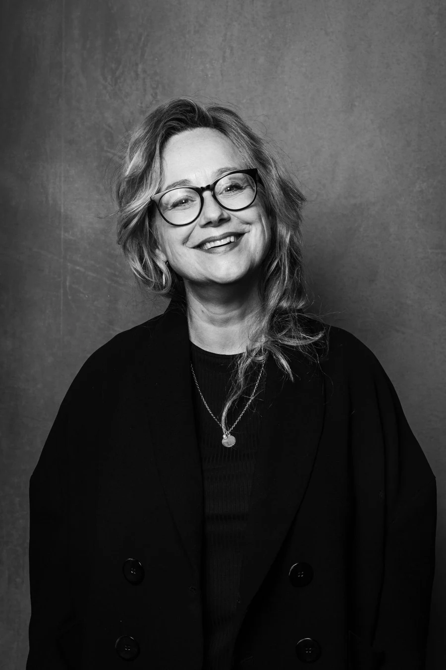 Astrid Bussink, photographed in black and white, smiling towards the camera.