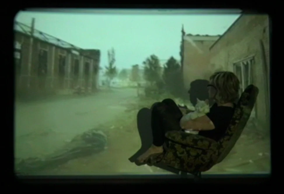 A person sits in an armchair in front of a projected street scene in Mijn Enschede.
